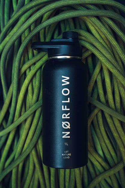 Botella térmica NORFLOW 1L negra sobre una cuerda de escalada verde enrollada